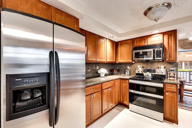 kitchen with light tile patterned floors, a textured ceiling, decorative backsplash, and appliances with stainless steel finishes