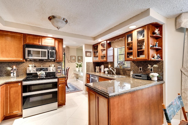 kitchen featuring a textured ceiling, brown cabinets, a sink, and appliances with stainless steel finishes