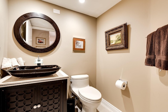 bathroom with toilet, vanity, and baseboards
