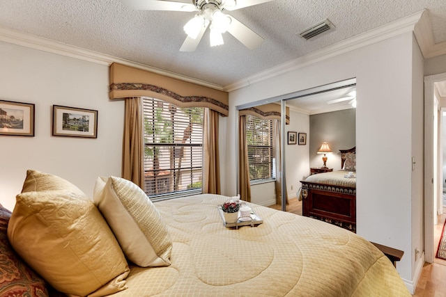 bedroom featuring crown molding, baseboards, visible vents, and a textured ceiling