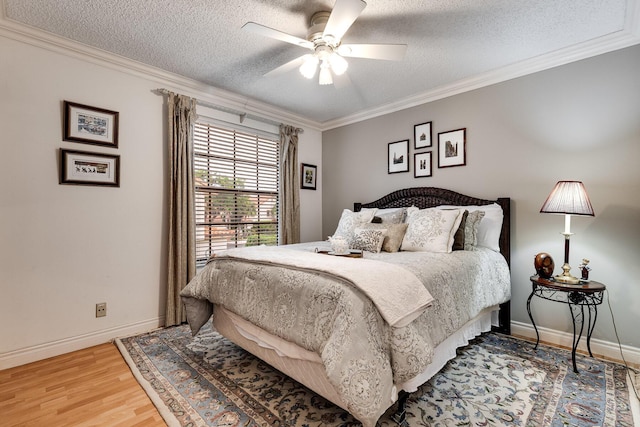 bedroom with ornamental molding, light wood-style flooring, baseboards, and a textured ceiling