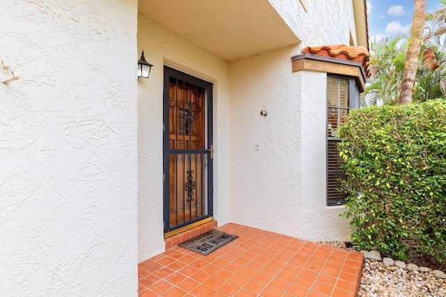 doorway to property featuring stucco siding and visible vents