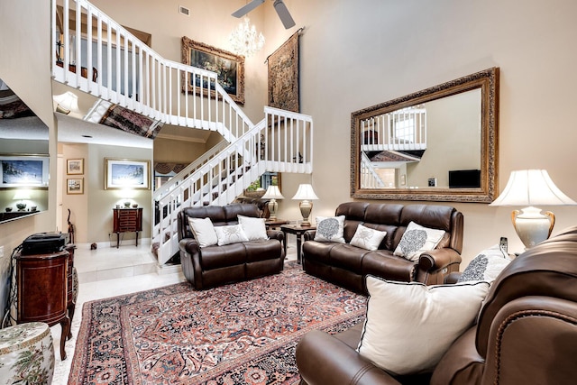 living area with visible vents, baseboards, a towering ceiling, and stairs
