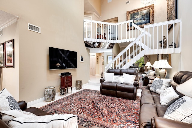 living room featuring baseboards, a high ceiling, crown molding, stairs, and visible vents