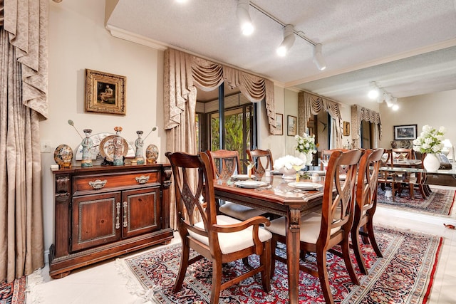 dining room featuring rail lighting, light tile patterned floors, a textured ceiling, and ornamental molding