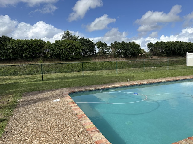 view of swimming pool with fence and a lawn
