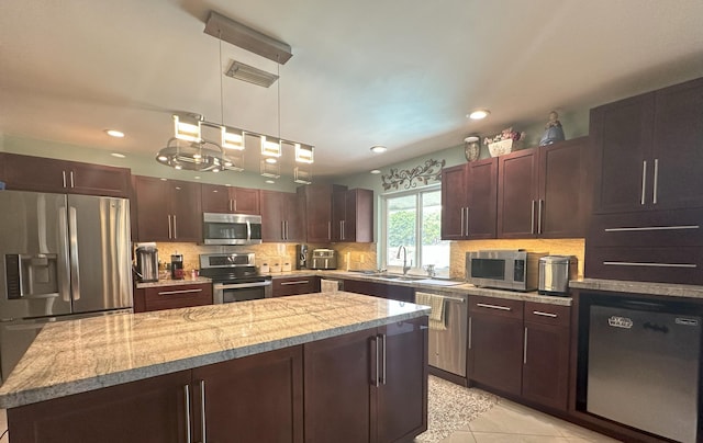 kitchen featuring a center island, a sink, stainless steel appliances, tasteful backsplash, and recessed lighting
