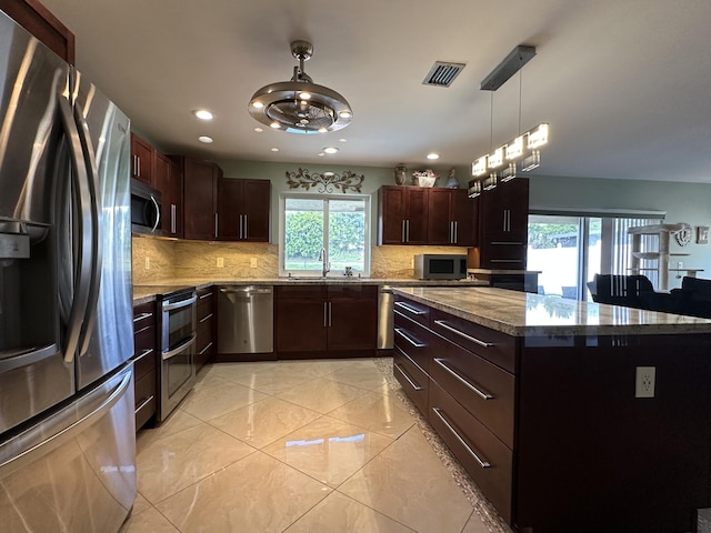 kitchen with a sink, stainless steel appliances, visible vents, decorative light fixtures, and decorative backsplash