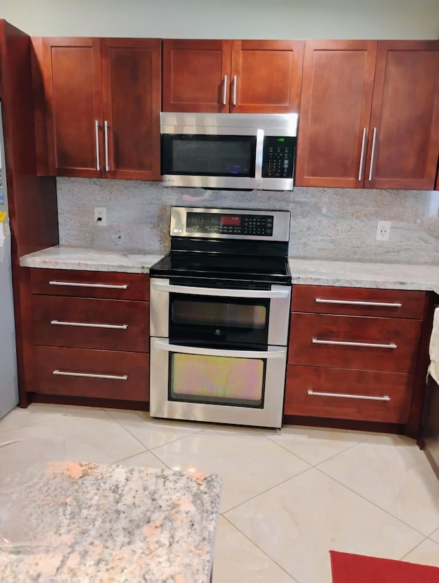 kitchen with light tile patterned flooring, tasteful backsplash, light countertops, and appliances with stainless steel finishes