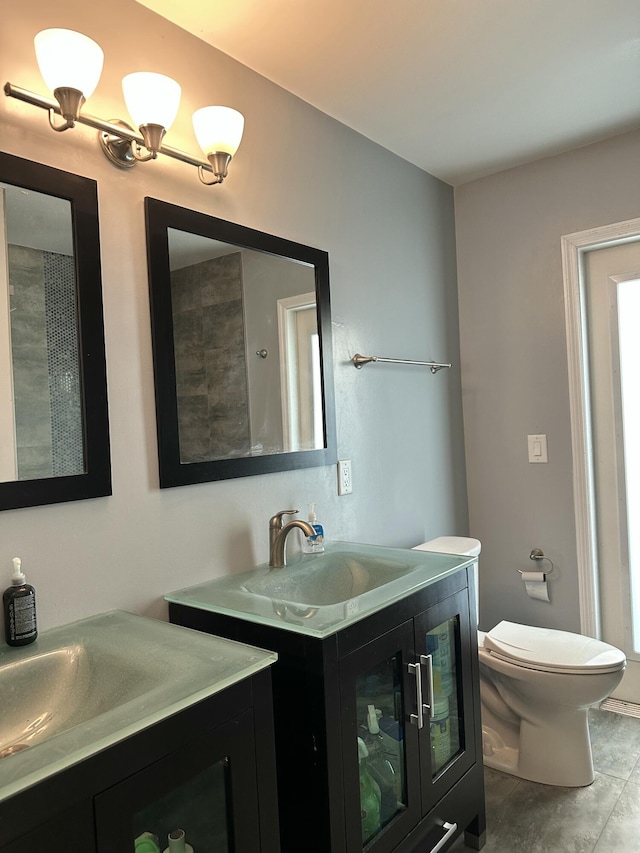 full bath featuring a sink, toilet, and two vanities