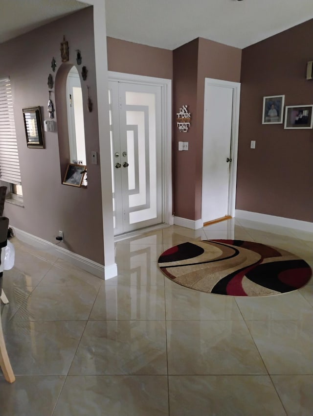 entryway featuring light tile patterned flooring, arched walkways, and baseboards