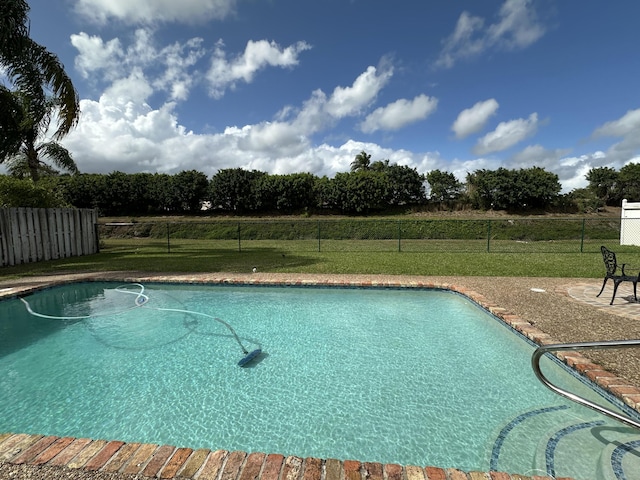 view of swimming pool featuring a lawn, a patio area, a fenced in pool, and fence