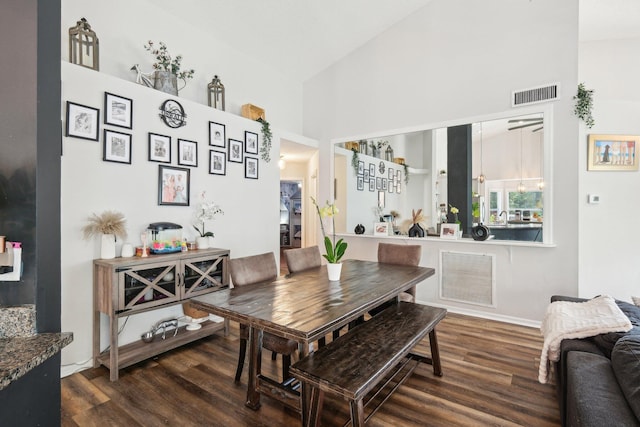 dining space with a towering ceiling, wood finished floors, and visible vents