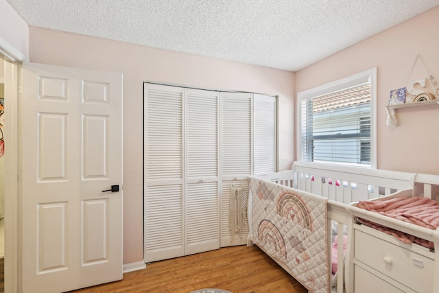 bedroom with a closet, light wood-style flooring, and a textured ceiling