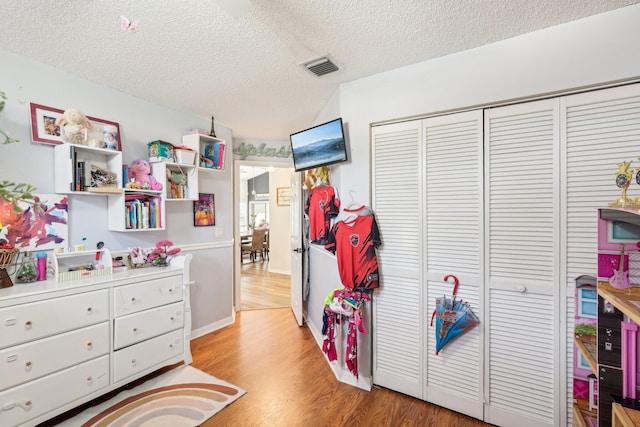 bedroom featuring a closet, light wood finished floors, a textured ceiling, and visible vents