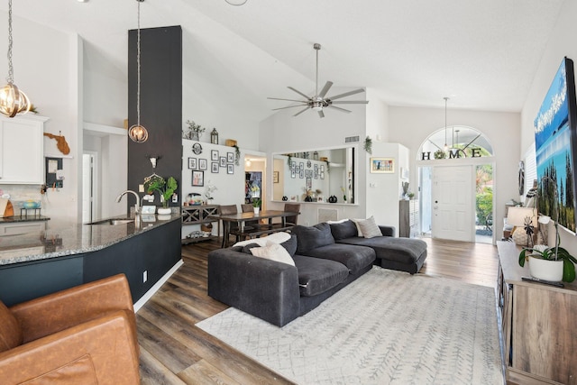 living area with visible vents, a ceiling fan, dark wood-style floors, and high vaulted ceiling