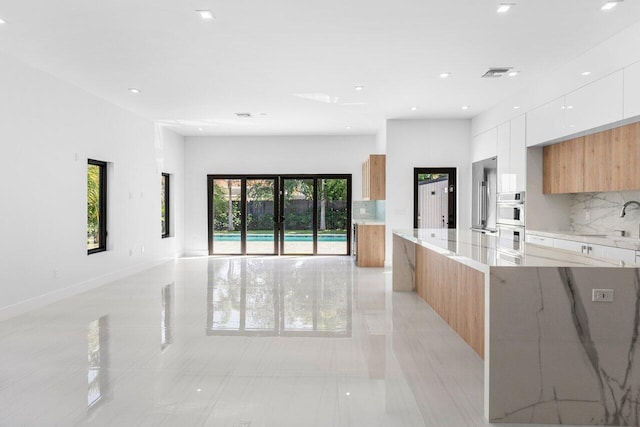 306 Plymouth Rd, West Palm Beach, FL 33405 - kitchen with modern cabinets, light stone countertops, visible vents, open floor plan, and backsplash