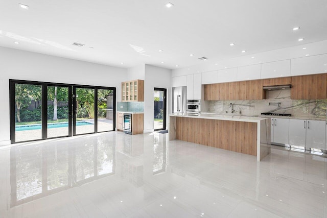 306 Plymouth Rd, West Palm Beach, FL 33405 - kitchen featuring modern cabinets, ventilation hood, white cabinets, appliances with stainless steel finishes, and backsplash
