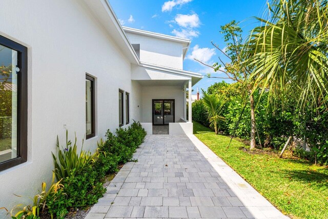 306 Plymouth Rd, West Palm Beach, FL 33405 - property entrance with stucco siding, french doors, and a lawn
