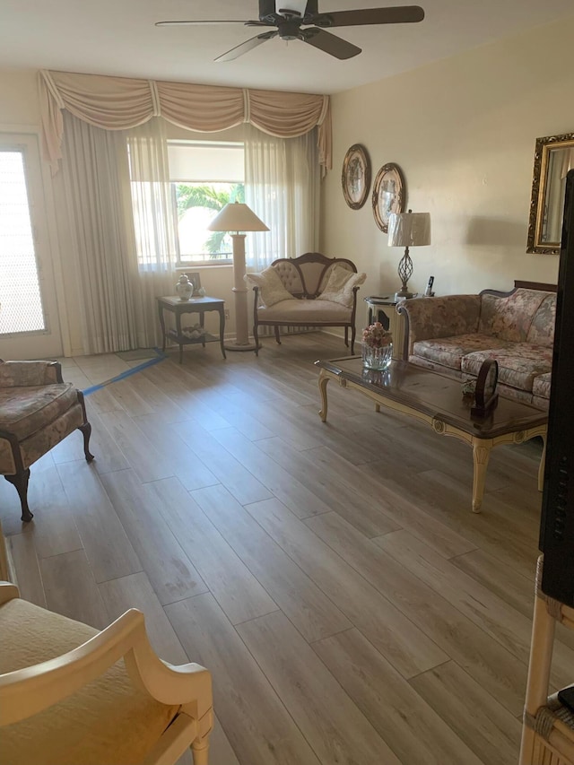 living area with a ceiling fan, wood finished floors, and a healthy amount of sunlight