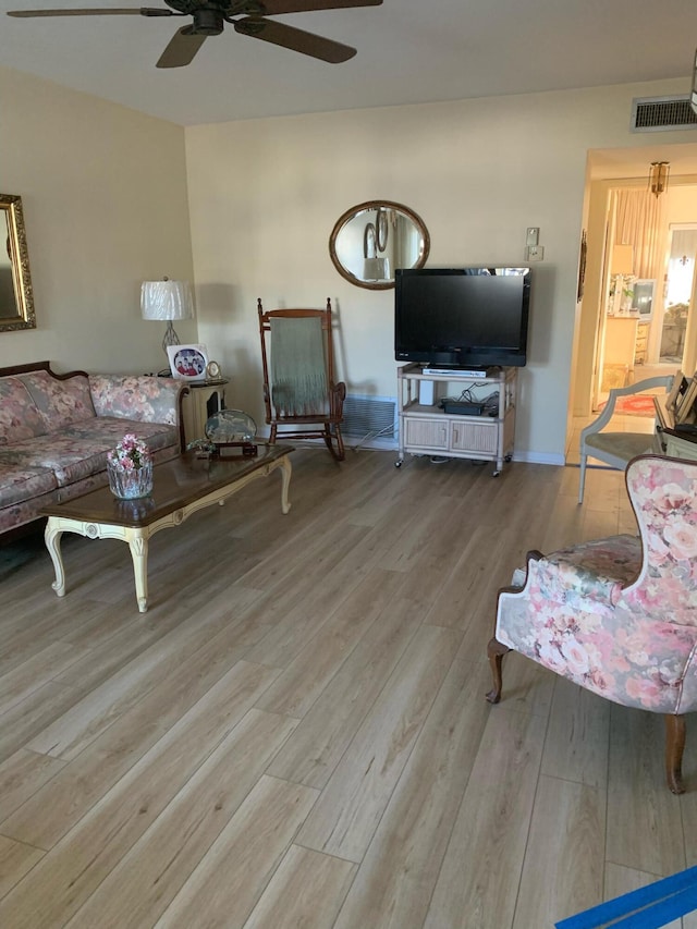 living area with wood finished floors, baseboards, a ceiling fan, and visible vents