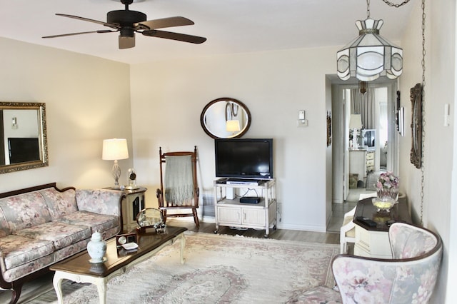living room with ceiling fan, wood finished floors, and baseboards
