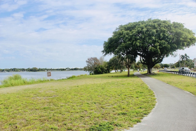 surrounding community with a water view and a yard