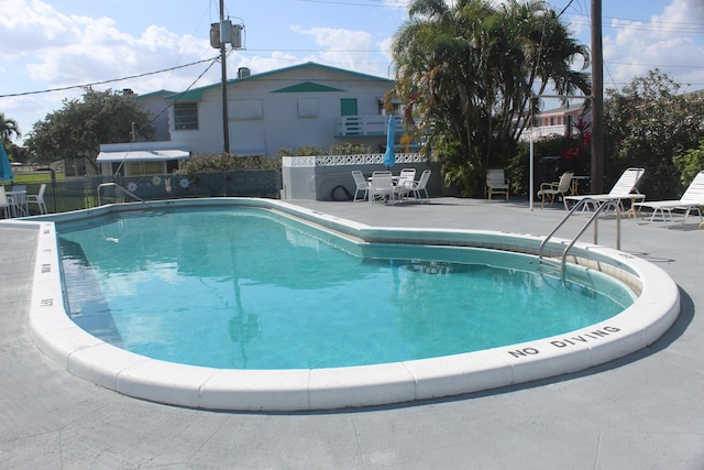 community pool with a patio area and fence