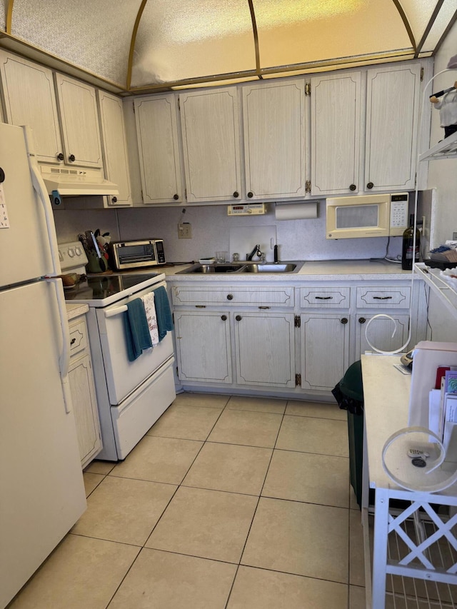 kitchen with under cabinet range hood, white appliances, light countertops, and light tile patterned floors