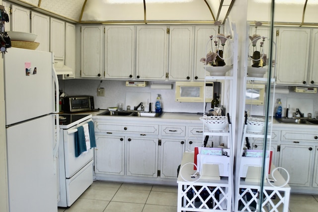 kitchen with a sink, light countertops, white appliances, and light tile patterned flooring