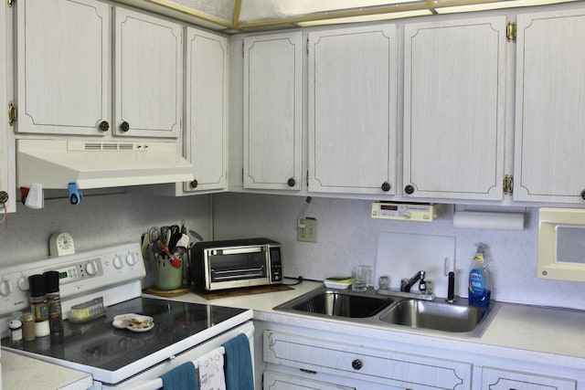 kitchen with white range with electric cooktop, under cabinet range hood, light countertops, a sink, and a toaster