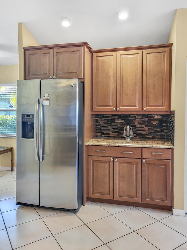 12404 Lakeridge Falls Dr, Boynton Beach, FL 33437 - kitchen with stainless steel refrigerator with ice dispenser, brown cabinetry, backsplash, and light stone counters