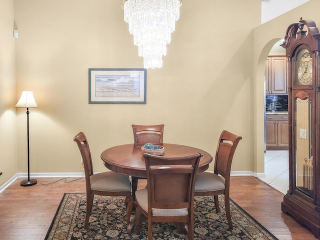 12404 Lakeridge Falls Dr, Boynton Beach, FL 33437 - dining area with arched walkways, light wood finished floors, baseboards, and a notable chandelier