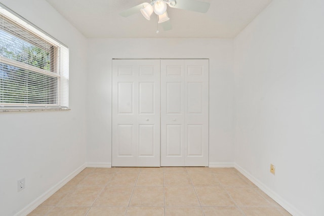 unfurnished bedroom with light tile patterned flooring, baseboards, ceiling fan, and a closet