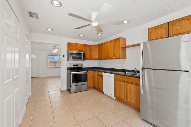 kitchen featuring visible vents, ceiling fan, brown cabinets, a sink, and stainless steel appliances
