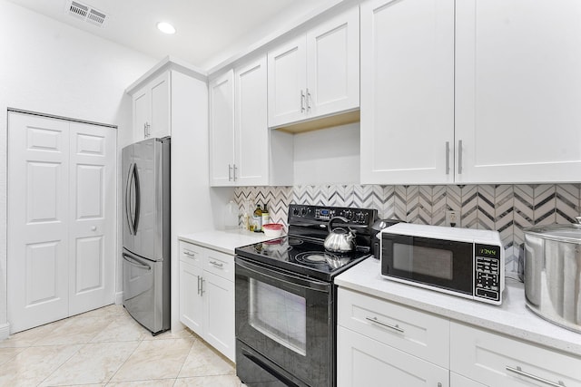 600 NW 24th Ave, Boynton Beach, FL 33426 - kitchen with black electric range, freestanding refrigerator, white cabinetry, backsplash, and recessed lighting