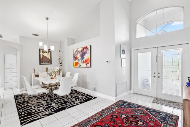 entrance foyer featuring arched walkways, visible vents, high vaulted ceiling, and light tile patterned floors