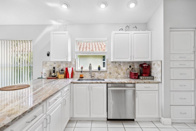 kitchen featuring white cabinets, stainless steel dishwasher, a sink, tasteful backsplash, and light stone counters
