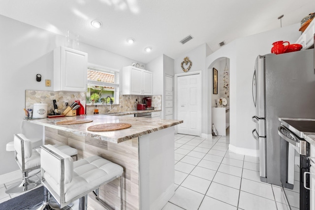 kitchen with white cabinets, stainless steel appliances, a peninsula, visible vents, and backsplash