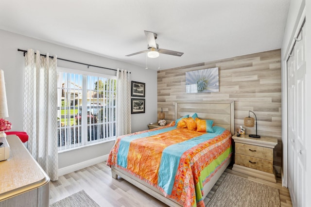 bedroom with wood finished floors, a closet, tile walls, ceiling fan, and baseboards