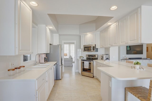 kitchen featuring a sink, white cabinets, stainless steel appliances, and a peninsula