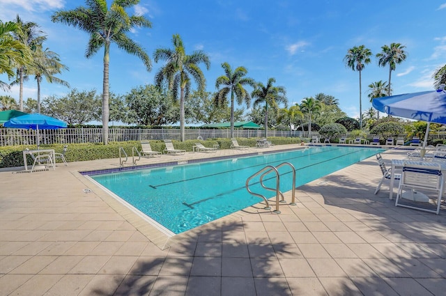 community pool with a patio and fence