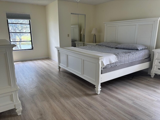 bedroom featuring light wood finished floors and baseboards