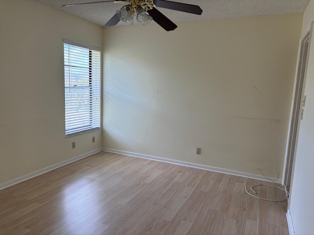 empty room featuring a textured ceiling, light wood-style flooring, baseboards, and ceiling fan