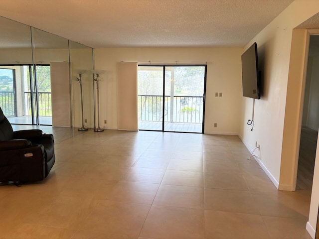 living room with baseboards, a textured ceiling, light tile patterned floors, and plenty of natural light