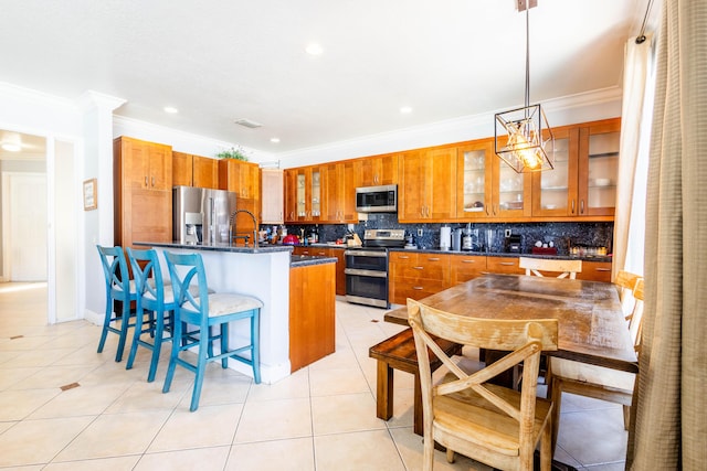 kitchen with backsplash, brown cabinetry, crown molding, and appliances with stainless steel finishes
