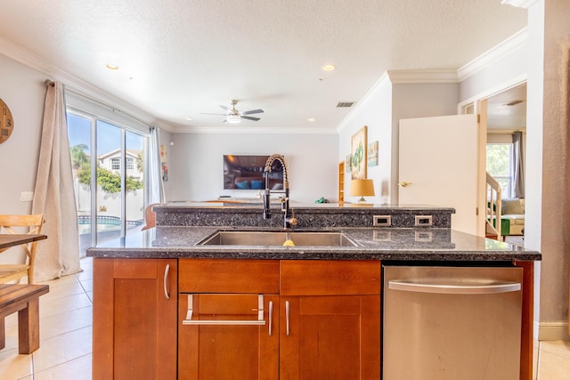 kitchen with dark stone countertops, open floor plan, a kitchen island with sink, dishwasher, and a sink