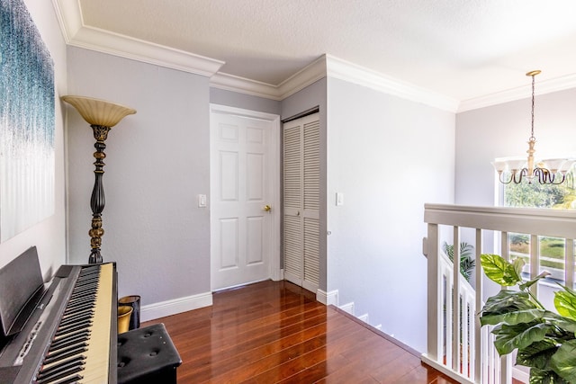 corridor with crown molding, wood finished floors, a notable chandelier, and baseboards