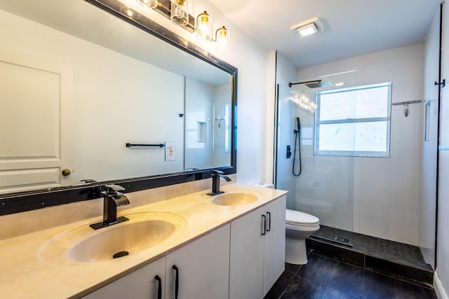 bathroom with a sink, toilet, a tile shower, and tile patterned flooring