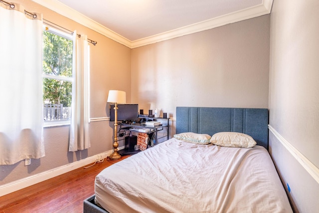 bedroom with wood finished floors, baseboards, and ornamental molding